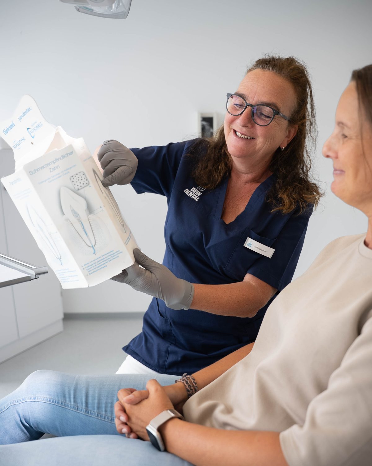 Zahnärztin erklärt einer Patientin die Behandlung am Modell